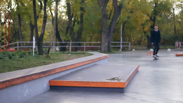 Hipster skateboarder montar y saltar en un parque de skate. Disparo en cámara lenta — Vídeos de Stock