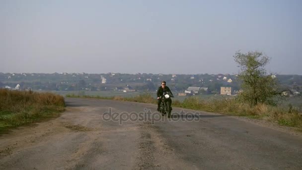 Widok z przodu stylowe fajne młodego człowieka w okularach słonecznych i skórzana kurtka jazdy jego chopper na drogę asfaltową na słoneczny dzień — Wideo stockowe