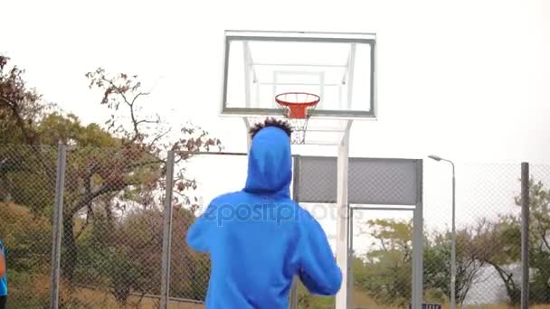 Νεαρός αφρικανική αμερικανική παίζει μπάσκετ στην οδό και ρίχνει μια μπάλα στο καλάθι, ανεπιτυχώς. Slowmotion βολή — Αρχείο Βίντεο