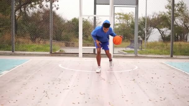 Fiatal afro-amerikai gyakorló kosárlabda kívül. Slowmotion lövés — Stock videók