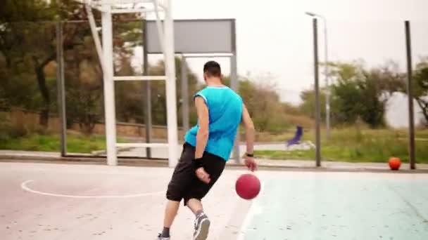 Trackshot eines jungen Mannes, der mit einem Ball rennt und einen Ball erfolgreich zum Korb wirft. Basketballspiel. Zeitlupenschuss — Stockvideo