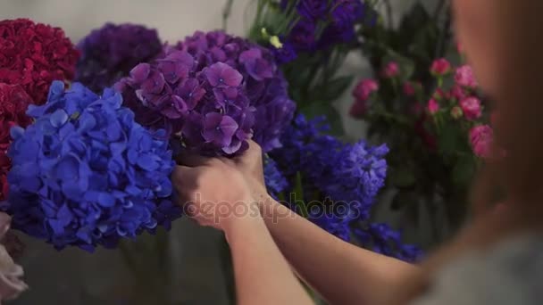 Πίσω όψη του ιδιοκτήτη επιχείρησης αγνώριστη γυναίκα ανθοκόμος εργασίας και την προετοιμασία των ρυθμίσεων λουλουδιών στο μαγαζί της, με φρέσκα λουλούδια. Slowmotion βολή — Αρχείο Βίντεο