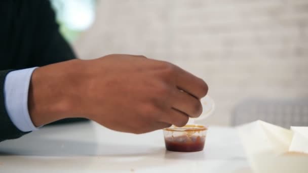 Jovem afro-americano mergulha nugget de frango em molho e come olhando para a câmera durante o almoço no trabalho em câmera lenta — Vídeo de Stock