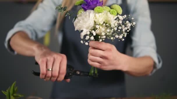 Vista ravvicinata di mani di artista floreale femminile professionale che prepara un mazzo, fiorista che taglia steli di fiore a negozio di fiori. Fioreria, artigianato e concetto di piccola impresa — Video Stock