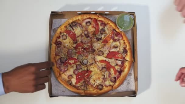 手をテーブルの上に紙箱からピザのカットを撮影します。平面図です。認識できない人々 が同時に広がって腕ピザのスライスを取得します。飢えた人々 と食事注文のグループ — ストック動画