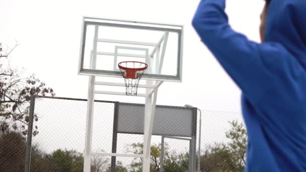 Junger Afroamerikaner spielt Basketball auf der Straße und wirft erfolgreich einen Ball in den Korb. Zeitlupenschuss — Stockvideo