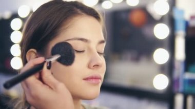 Kadın el yüz toz özel fırça kullanarak genç kadının cilt üzerinde closeup görünümü. Slowmotion atış