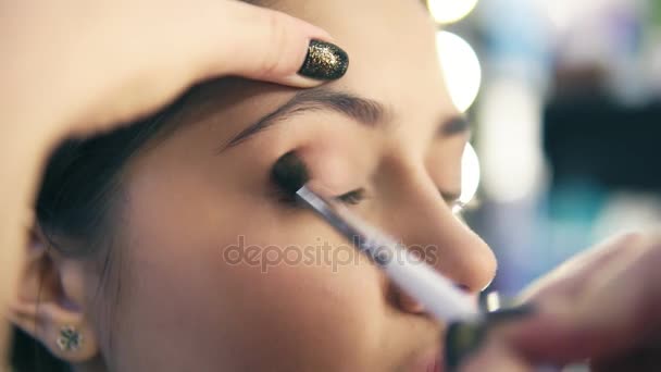 Close-up beeld van professionele make-up artiest handen met behulp van make-up borstel toe te passen eye shadows. Pro visagiste zet licht bruin schaduwen op ooglid van een model. Tikje schot — Stockvideo