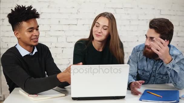 白いノート パソコンの周りに座っている間論争の若い起業家の多様なグループです。彼らは良い決定を見つけようとして、オフィスで事業を検討しています。スローモーション — ストック動画