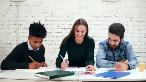 Feliz grupo diverso de estudiantes o equipo de negocios jóvenes que trabajan en un proyecto. Jóvenes estudiantes preparando sus deberes juntos — Vídeos de Stock