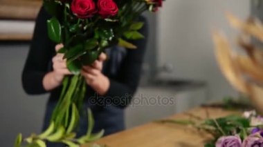 Genç çekici kadın Çiçekçi Çiçek dükkanında güzel kırmızı gül buketi düzenlenmesi. Slowmotion atış