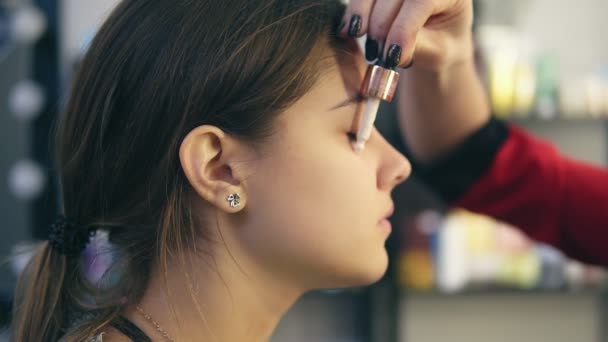 Maskenbildnerin trägt Concealer auf das Gesicht eines jungen Mädchens auf. Basis für perfektes Make-up. Zeitlupenschuss — Stockvideo