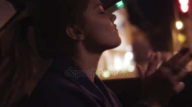 Güzel bir kız üzerinde arka koltukta oturan ve müzik kafasını hareket gece taksiye binme. Mutlu kadın taksi. Gece canlı. Slowmotion atış