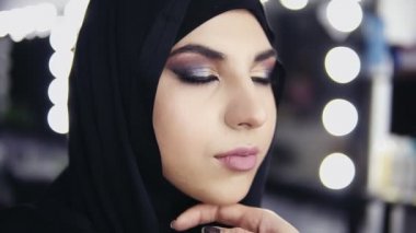 Özel fırça kullanarak Müslüman kadının gözleri göz farı uygulamak profesyonel makyöz elinde. Hijab Güzellik Salonu içinde genç bir kadın. Güzellik, makyaj ve moda kavramı. Slowmotion atış