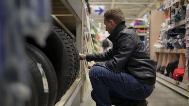 Süpermarkette otomobil lastikleri raflarda duran seçerek genç adam