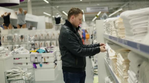 Jonge man kiest handdoeken in de winkel — Stockvideo