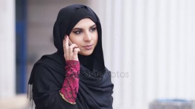 Cep telefonunu bir numarayı aramadan hijab ayakta sokakta, giyen genç çekici kadın. Slowmotion atış