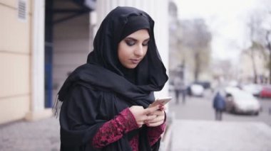 Cep telefonu üzerinde tipik bir haber hijab ayakta sokakta, giyen genç çekici kadın. Slowmotion atış