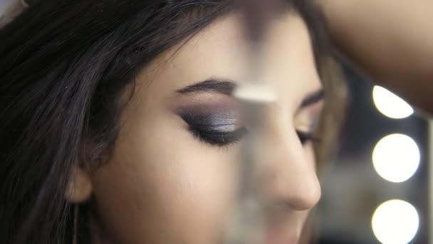 Händerna på professionella make-up artist gäller modeller ögat använder speciell borste ögonskugga. Skönhet, smink och mode koncept. Slowmotion skott — Stockvideo