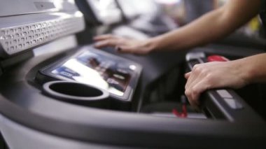 Kadın bodbuilder kurma bir program ve zaman ayarlı koşu bandı koşu başlatmak için hazırlık spor salonunda ayarla