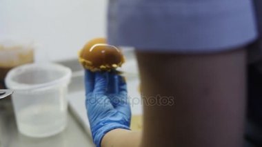 Pudra mavi eldiven karamel camlı pasta vitrinde daha sonra bu koymak için özel altın karton Tabaklarda koyar. Lezzetli tatlılar. Güzel yemek-art.
