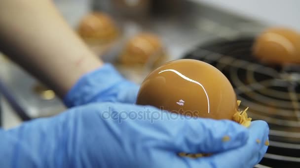 Proceso de creación de deliciosos postres. los confiteros irreconocibles por las manos en los guantes azules quitan los pasteles de la bandeja y adornan con las patatas fritas. Imágenes de primer plano — Vídeos de Stock