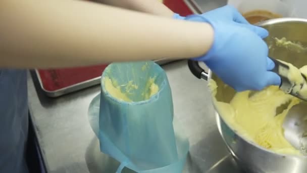 Mettere la pasta prodotta in un tubo pasticceria. Processo di fabbricazione della pasticceria tradizionale francese. Preparazione di eclaires o profiteroles . — Video Stock