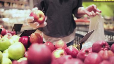 Kadın Kırmızı elma vasıl belgili tanımlık bakkal stok seçme. Elma meyve ve sebze reyonunda bir süpermarket dışarı kadının el alır
