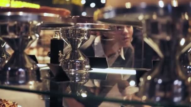 Joven hermosa chica mirando a través de la ventana en la pastelería en el pasillo de la panadería de la tienda de comestibles se levanta para comprar algunos postres . — Vídeo de stock