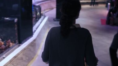 Ne satın almak için karar vermeye çalışan bir süpermarket koridorda yürürken kıvırcık saçlı bir kadın müşteri görüntülerini arka