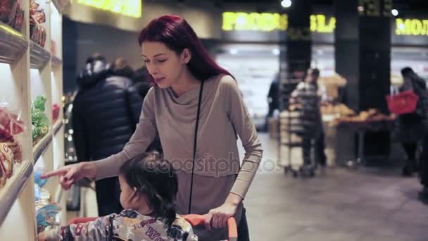 La joven con su hijo pequeño está eligiendo pan en la tienda de comestibles local. Imágenes de Slomo . — Vídeo de stock