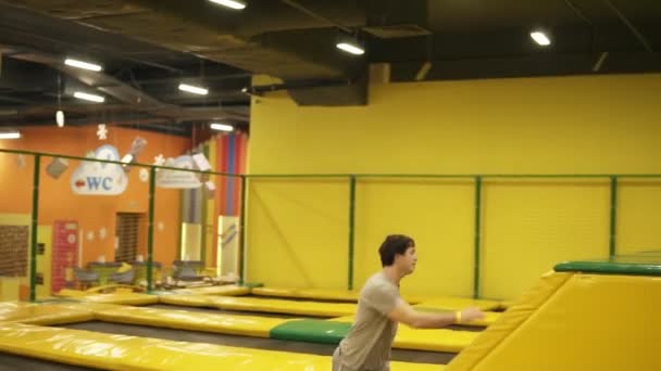 Giovane maschio bruno attraente sorvola barriera gialla al trampolino professionale. Giovani, sport, ginnastica . — Video Stock