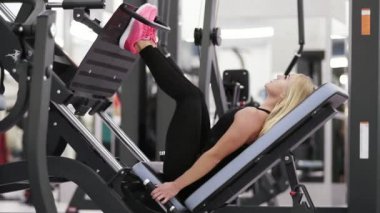 Spor salonunda egzersiz genç güzel sarışın kadın. Güçlü glutes kadar bina, hamstrings ve kalça bacak üzerinde makinesi tuşuna basın. Yaşam tarzı.