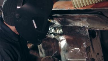 Kaynak maskesi içinde kaynak bir fabrikada erkek işçi çekiç tanımlanamayan inşaat metal parçası bağlamak için kullanır. Endüstriyel bir tesisi üzerinde kaynak. Ağır çekim.