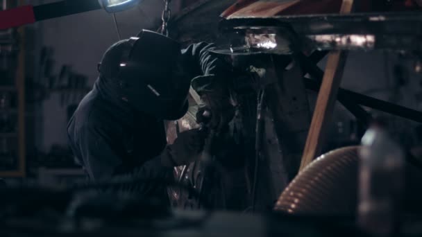 Soldador trabalhando no lado inferior do carro em um hangar mecânico . — Vídeo de Stock