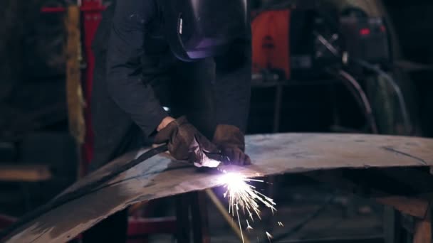 Unrecognizable workman all equiped with protective wear cuts piece of mettal with an industrial cutting torch using woodplank to adjust it. — Stock Video