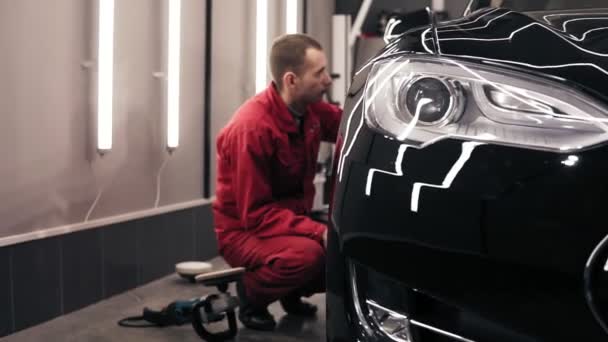 Trabalhador Autocenter fazendo a limpeza final do carro preto novo perfeitamente polido . — Vídeo de Stock