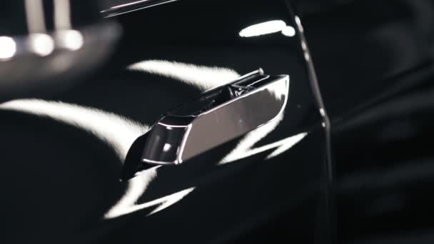 Slomotion beelden van chroom gelooid deurklink trekt uit en vervolgens weer in de deur van een nieuwe zwarte auto. — Stockvideo