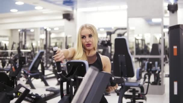 Mujer joven culturista en ropa deportiva negro haciendo exersices en el gimnasio. Construyendo músculos fuertes del núcleo y de los brazos — Vídeos de Stock