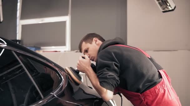 Uomo in onezie rosso lucidatura auto nera . — Video Stock