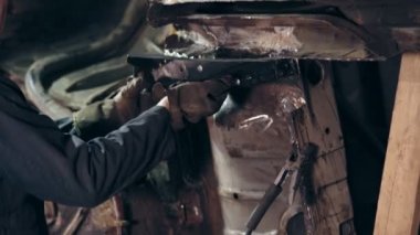 Erkek workeres workclothes araba alt yüzey dur. Bir işçi kaplin fındık kullanarak araba inşaat metal ayrıntılarına ayarlar.