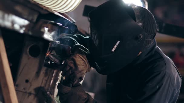 Male worker at a welding factory in a welding mask. Welding on an industrial plant. Slow motion. — Stock Video