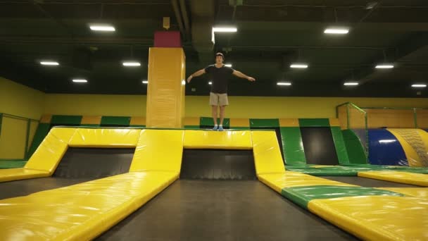 Замедленная съемка молодого спортсмена, развлекающегося прыжками на профессиональном батуте, делающего сальто . — стоковое видео