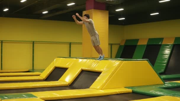 Gele overdekte trampoline voor jonge sportieve mensen. Atletische man uitvoert front salto's hoppen uit het platform. Jeugd, sport, Turnen. — Stockvideo