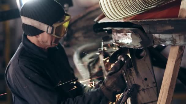 Workman met beschermende brillen is het slijpen van metalen constructie met cirkelzaag. — Stockvideo