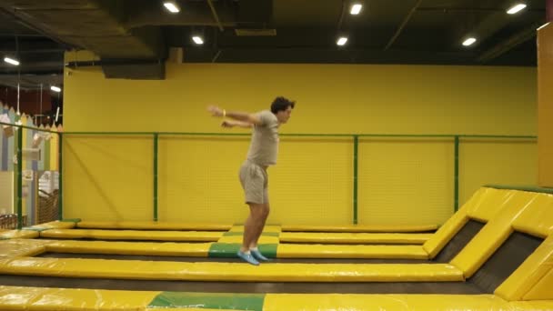 なによりダブルを選んだ以下におけるねじれ後方宙返りを実行しました。トランポリンでジャンプを楽しむ若い運動男性. — ストック動画