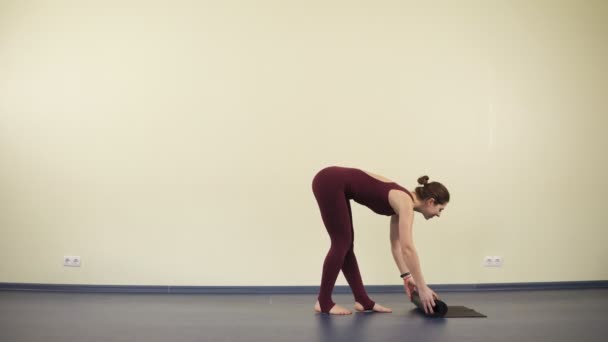 Mujer atractiva joven con cuerpo flexible y en forma comienza a practicar yoga en una esterilla negra — Vídeos de Stock