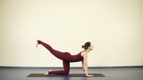 Mujer atractiva joven con cuerpo flexible y en forma hace ejercicios de yoga en estera negra, material de archivo interior. Estilo de vida saludable, hermoso cuerpo . — Vídeos de Stock