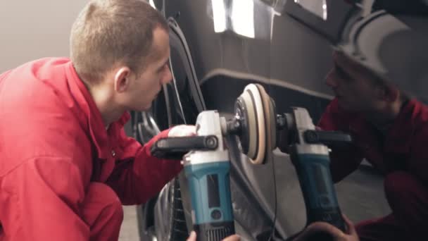 Pulido coche negro con una mashine profesional. Trabajador de autocenter en traje de trabajo rojo está limpiando cada milímetro de la nueva puerta lateral del coche Tesla . — Vídeos de Stock