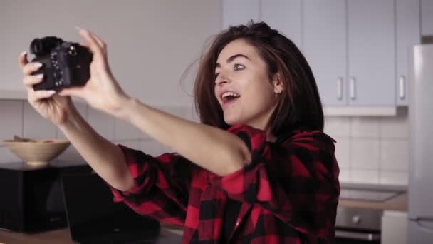 Jonge aantrekkelijke brunette meisje is het maken van grappige gezicht probeert te nemen van een selfie met professionele fotocamera. — Stockvideo